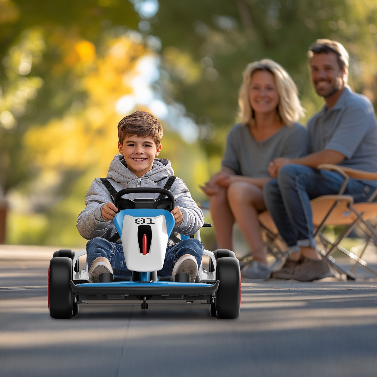 Child driving a toy car with parents sitting in the background